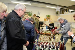 Menschen schauen sich Gläser an. Es sind viele Gläser nebeneinander. Es sieht aus wie ein Markt.