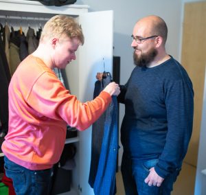 Zwei Männer stehen vor einem Schrank. Einer hält ein blaues Jackett.