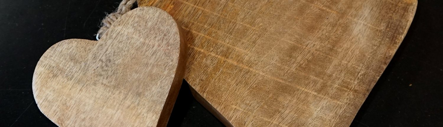 Holzherz mit Kordel vor dunklem Hintergrund.