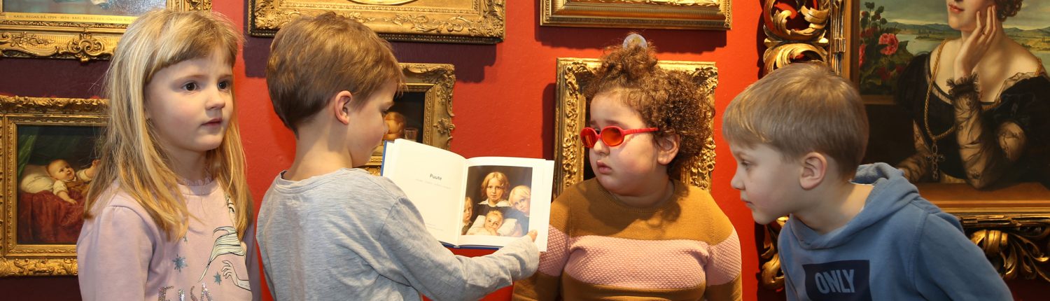 Kinder stehen vor einem Gemälde. Ein Junge hält ein Buch. Sie schauen alle auf das Bild.
