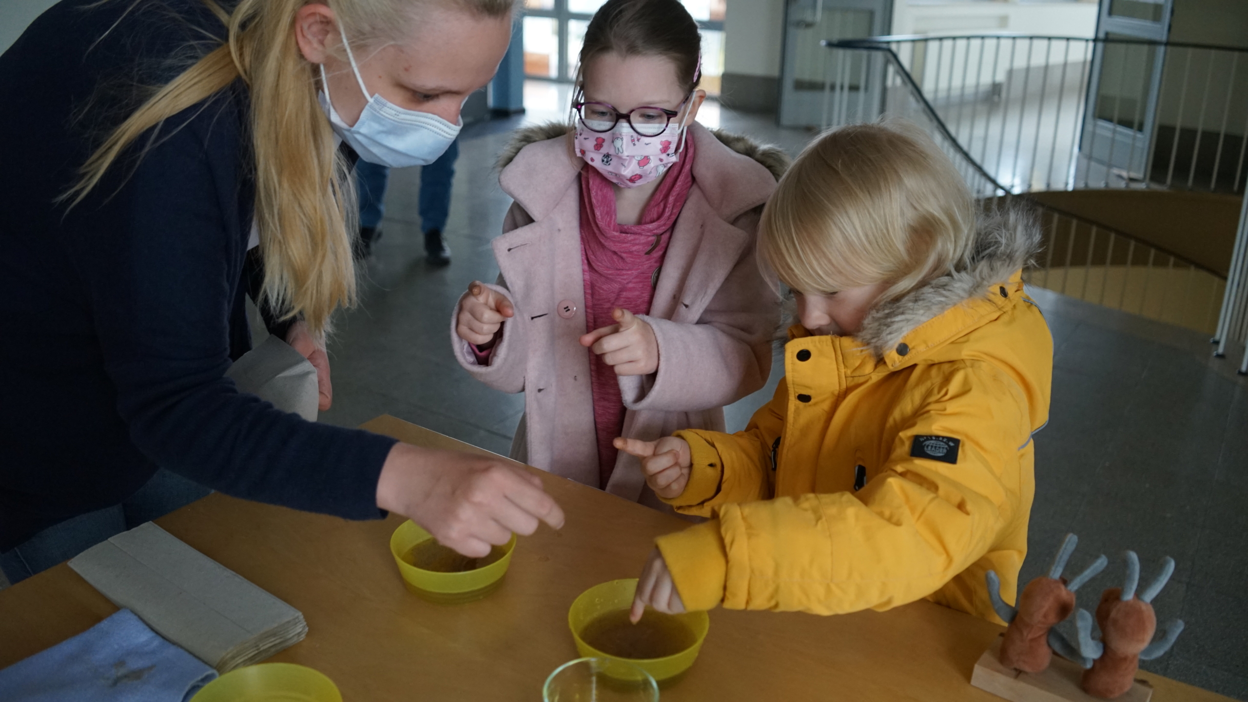 Zwei Kinder sitzen an einem Tisch. Ein Kind hat gelbe Ringe in der Hand.