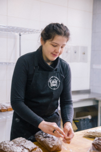 Eine Person bäckt Brot. Sie trägt eine Schürze und schaut auf den Teig.