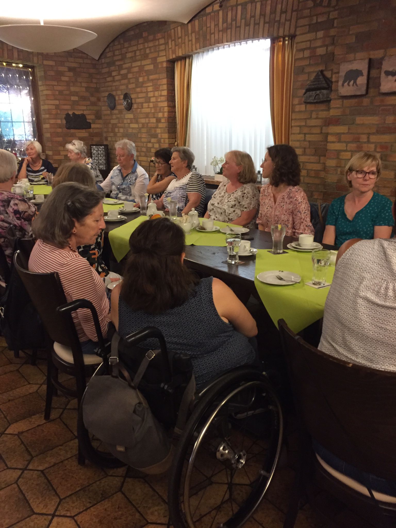 Gruppenfoto von Menschen, die an einem gedeckten Tisch in einem Restaurant sitzen. Die Teilnehmer sind in geselliger Runde versammelt und genießen ein gemeinsames Essen.