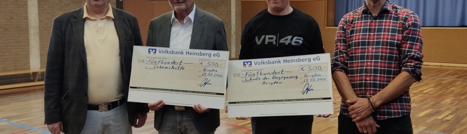 Vier Personen stehen in einem Saal und halten Urkunden oder Auszeichnungen in den Händen. Der Raum hat große Fenster und Holzboden. Die Veranstaltung scheint eine Ehrung oder Preisverleihung zu sein.