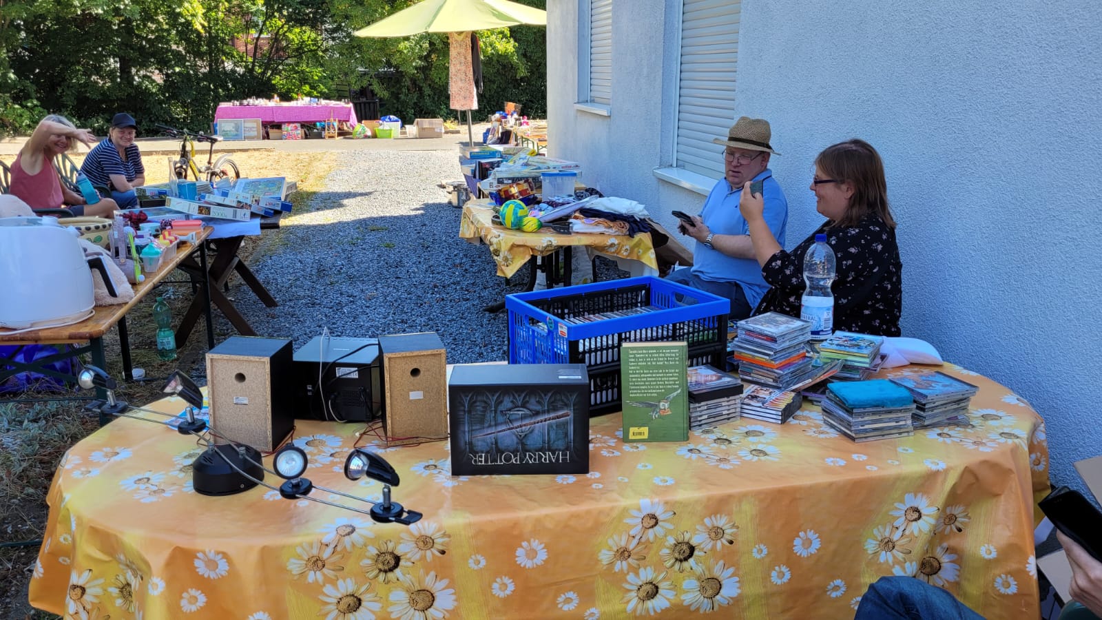 Ein Stand mit vielen Büchern, CDs und Dingen zum Kaufen. Zwei Männer schauen sich etwas an.