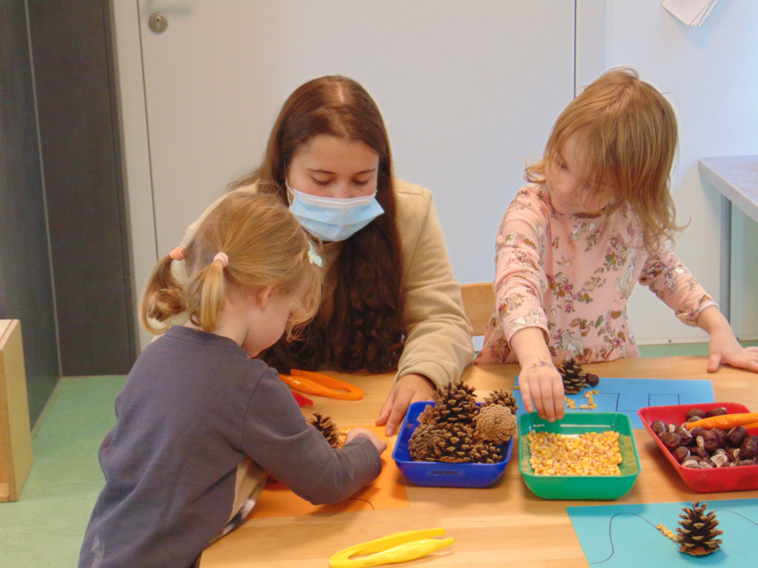 Kinder basteln mit Naturmaterialien am Tisch.