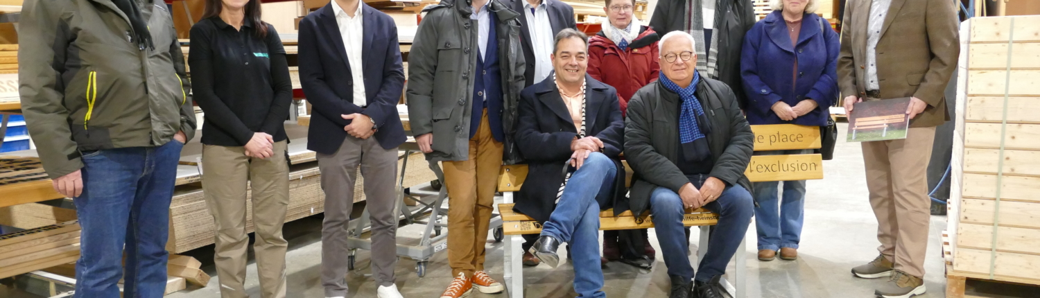 Gruppenfoto von acht Personen in einer Werkstatt, umgeben von Werkzeugen und Maschinen. Die Personen stehen und sitzen in einer freundlichen Pose, einige lächeln in die Kamera.