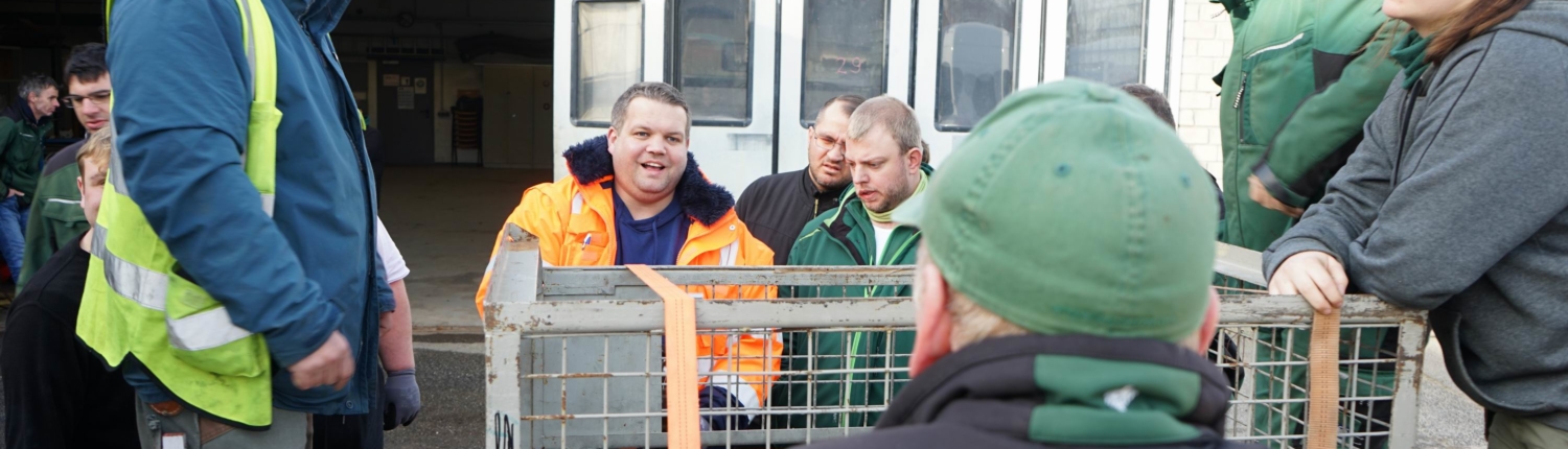 Gruppendiskussion von Fachleuten in Arbeitskleidung vor einem Transportfahrzeug, während sie sich auf eine Tierschutzmission vorbereiten.
