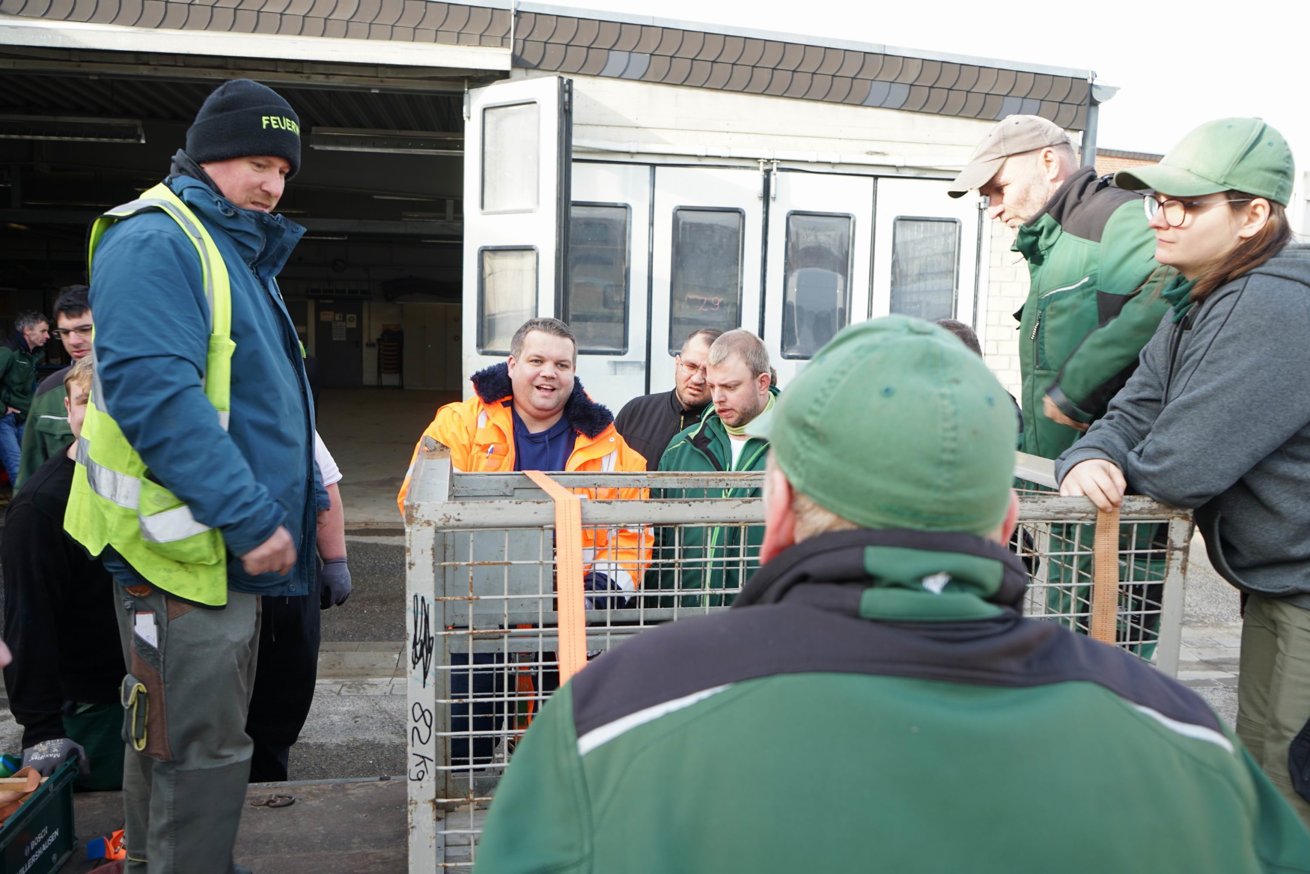 Gruppendiskussion von Fachleuten in Arbeitskleidung vor einem Transportfahrzeug, während sie sich auf eine Tierschutzmission vorbereiten.