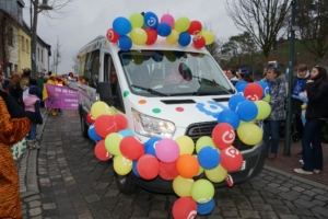 Ein Bus ist mit bunten Luftballons geschmückt. Menschen stehen daneben.