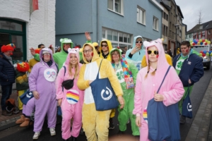 Gruppe von Menschen in bunten Kostümen, die fröhlich auf einer Straße posieren, umgeben von einer festlichen Atmosphäre.