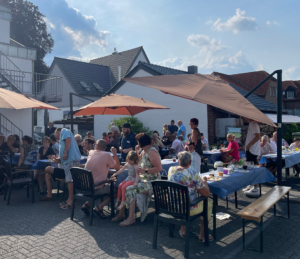 Menschen genießen eine gesellige Mahlzeit im Freien unter Sonnenschirmen in einem gemütlichen Restaurant.