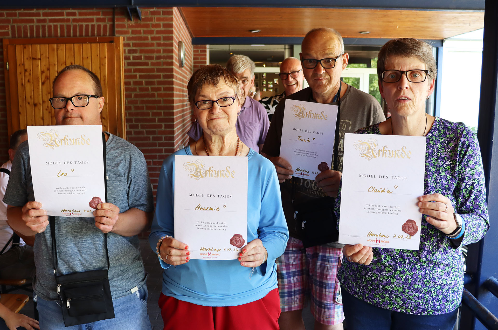 Gruppennfoto von vier Personen, die stolz ihre Zertifikate halten, in einem festlichen Ambiente. Ideal für Beiträge über Weiterbildung oder erfolgreiche Abschlüsse.