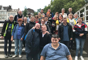 Gruppenfoto von einer großen Menschenmenge, die fröhlich im Freien posiert. Die Teilnehmer zeigen eine Vielfalt an Altersgruppen und Hintergründen, während sie gemeinsam Zeit verbringen und lächeln. Ideal für Veranstaltungen, Team-Building oder Gemeinschaftsaktivitäten.