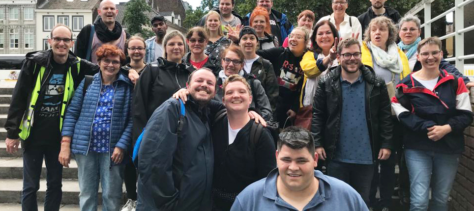 Gruppenfoto von einer großen Menschenmenge, die fröhlich im Freien posiert. Die Teilnehmer zeigen eine Vielfalt an Altersgruppen und Hintergründen, während sie gemeinsam Zeit verbringen und lächeln. Ideal für Veranstaltungen, Team-Building oder Gemeinschaftsaktivitäten.