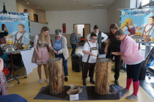 Menschen schlagen mit Äxten auf Holzstücke. Es ist ein Spiel auf einem Fest.