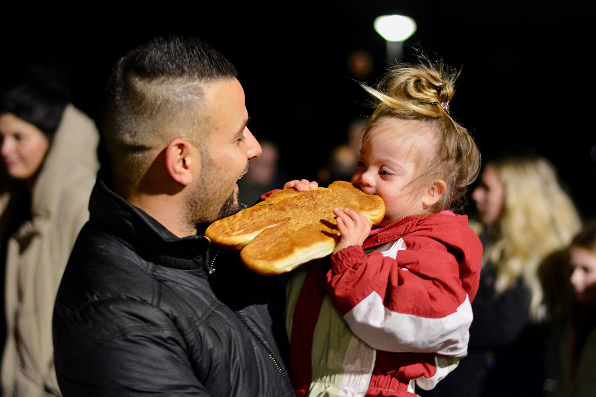 Vater und kleines Kind genießen gemeinsam ein großes Brot, während sie an einem Abend draußen stehen.