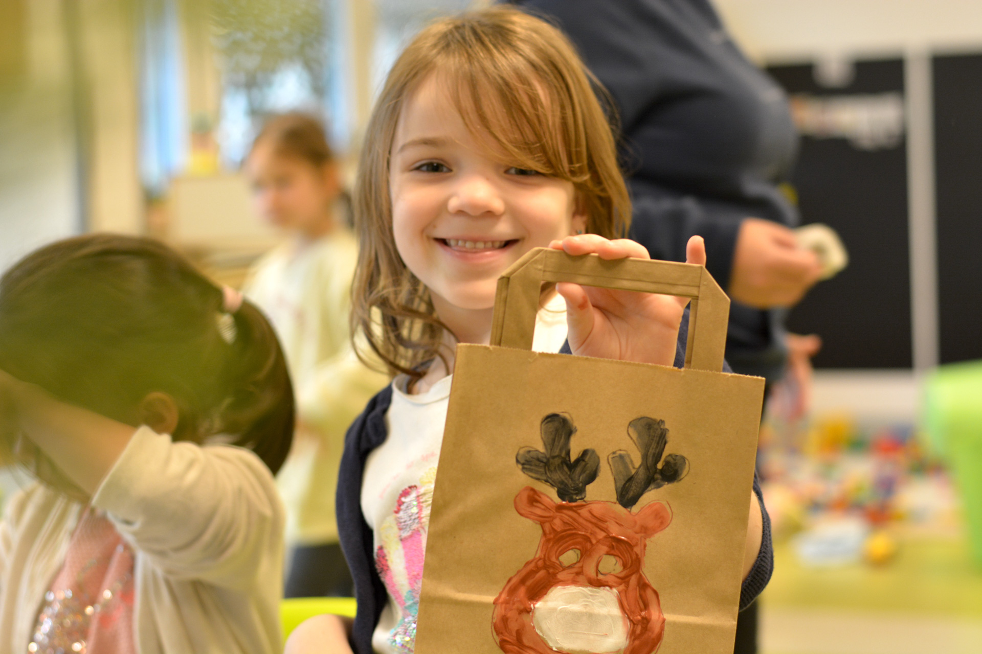 Ein Mädchen hält einen braunen Papiertüten mit einem Rentier-Bild.