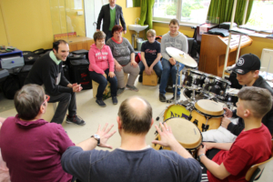 Eine Gruppe von Leuten sitzt im Kreis und macht Musik mit Schlagzeugen.