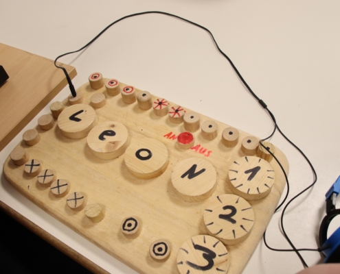 2023-12-15_Mike Musikgruppe (48) Holzstifte liegen auf einer Holzplatte. Daneben liegen Kopfhörer.