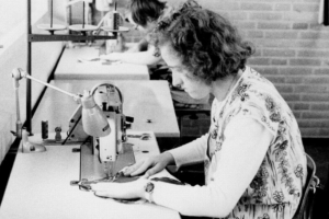 Eine Frau sitzt an einer Nähmaschine und näht etwas.