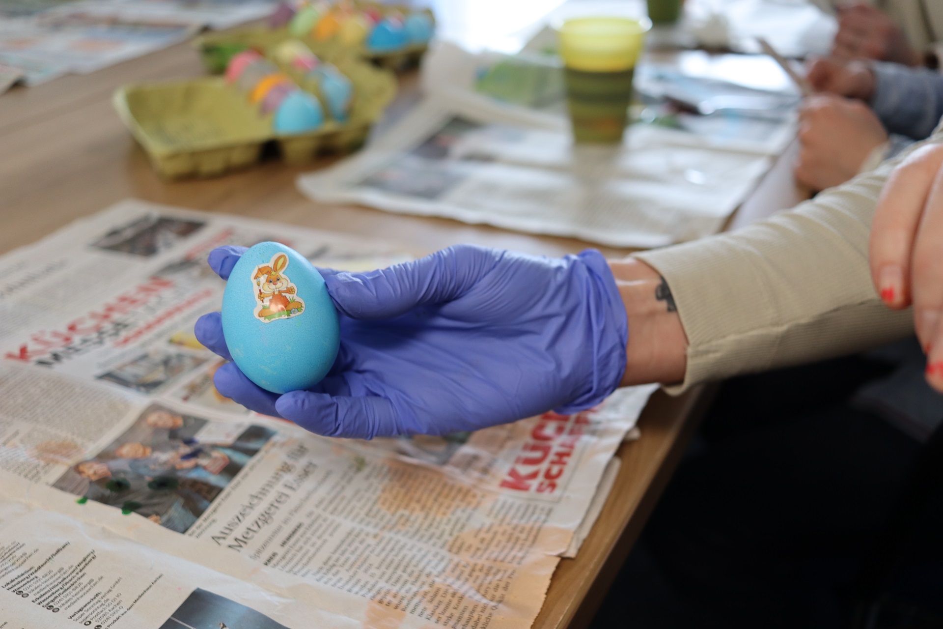 Ein blauer Osterei mit einem Hasen drauf. Jemand hält das Ei in der Hand.