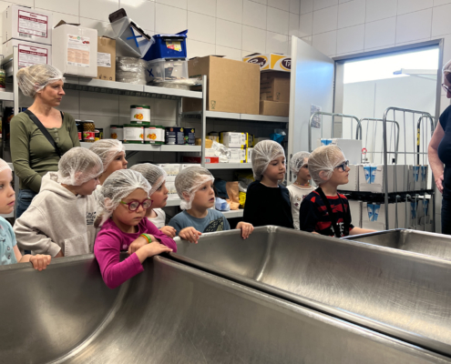 2024-05-16_Besuch Küche 1 (37)-2 Kinder in weißen Hauben stehen vor einem großen Waschbecken.