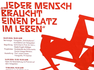 Ein weißes Schild mit schwarzem Text. Der Text ist schwer lesbar und enthält Informationen zu einer Veranstaltung.
