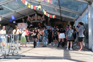 Viele Menschen stehen vor einer Bühne. Es gibt ein bisschen Musik.