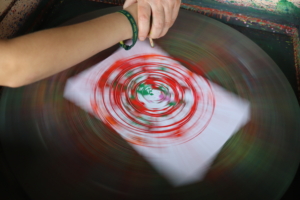 Eine Hand hält ein Papier mit roten und weißen Mustern.