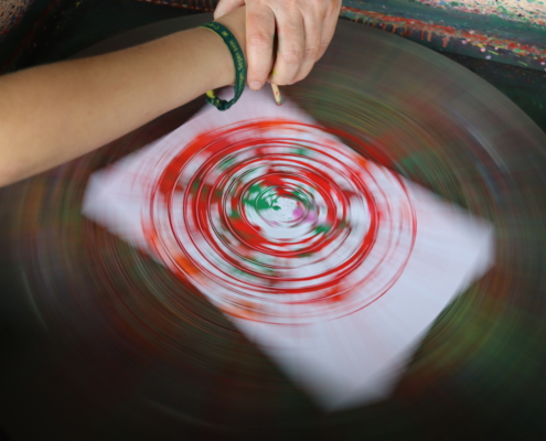 Eine Hand hält ein Papier mit roten und weißen Mustern.