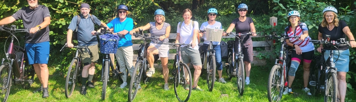 Gruppe von fünf Personen mit Fahrrädern im Freien, umgeben von grüner Natur, ideal für Fahrradtouren und Outdoor-Aktivitäten.