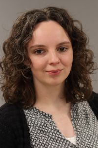 Rademacher, Bettina_2024 Porträt einer jungen Frau mit lockigem Haar und neutralem Gesichtsausdruck, geeignet für persönliche oder berufliche Profile.