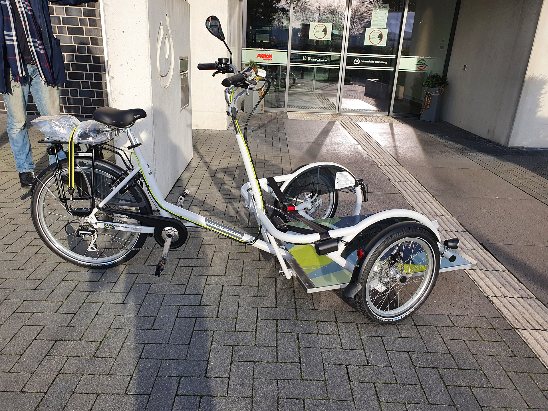 2021-12-09_Rollirad (10) Ein Fahrrad steht vor einem Gebäude. Es hat drei Räder.