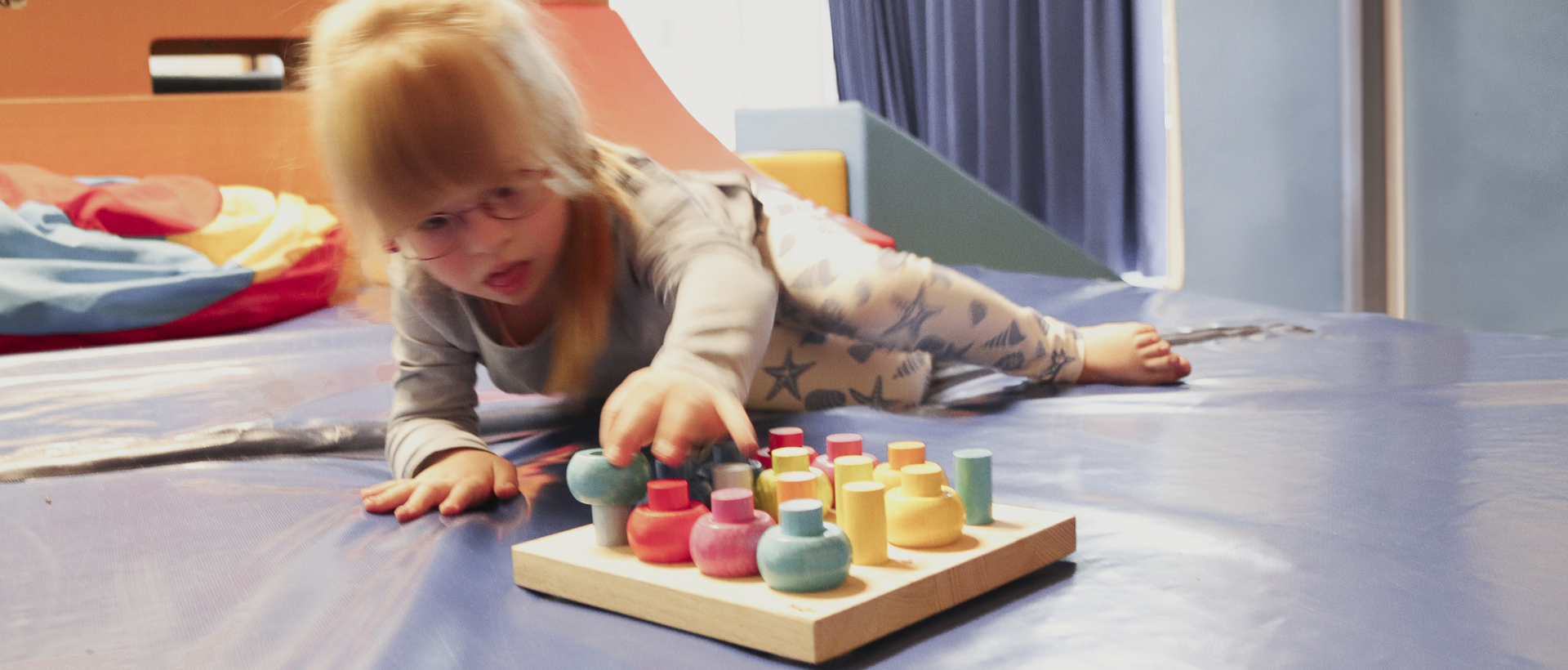 Ein kleines Mädchen spielt mit einem buntem Steckspiel.