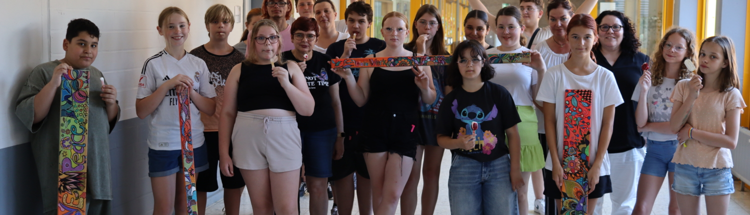 Gruppe von Schülern in einem Schulflur, die gemeinsam für ein Foto posieren, einige halten Bastelarbeiten in den Händen.