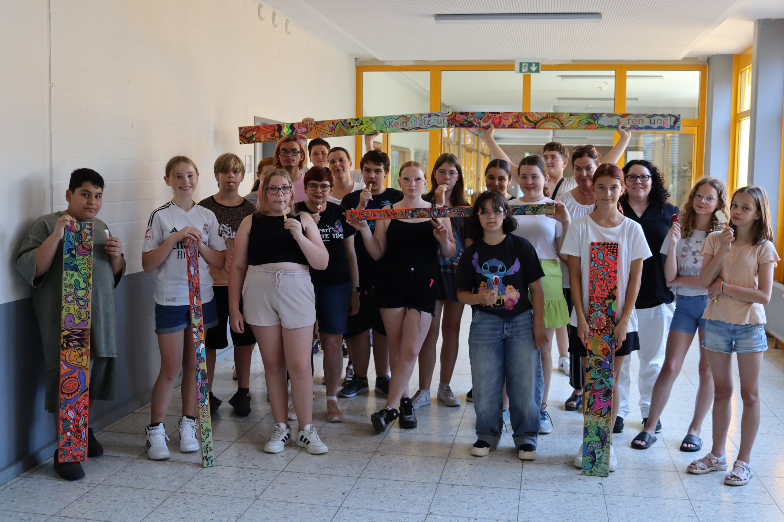 Gruppe von Schülern in einem Schulflur, die gemeinsam für ein Foto posieren, einige halten Bastelarbeiten in den Händen.