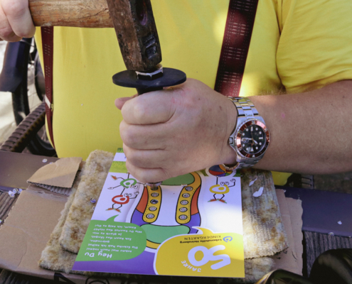 Ein Mann sitzt an einem Tisch und schlägt mit einem Stempel auf Flyer, um ihn zu löschern.