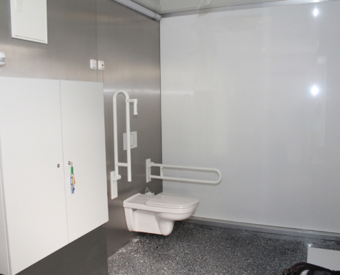Barrierefreies Badezimmer mit Toilette und Haltegriffen.