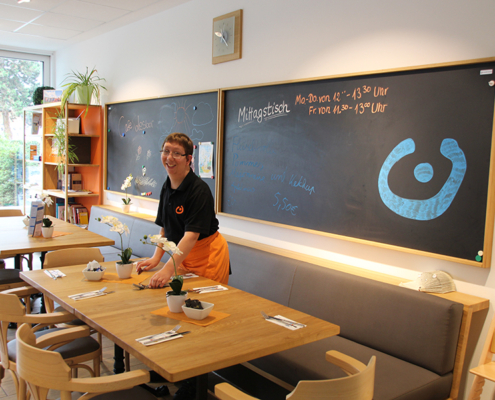 Ein Kellner steht lächelnd an einem Tisch in einem Restaurant.