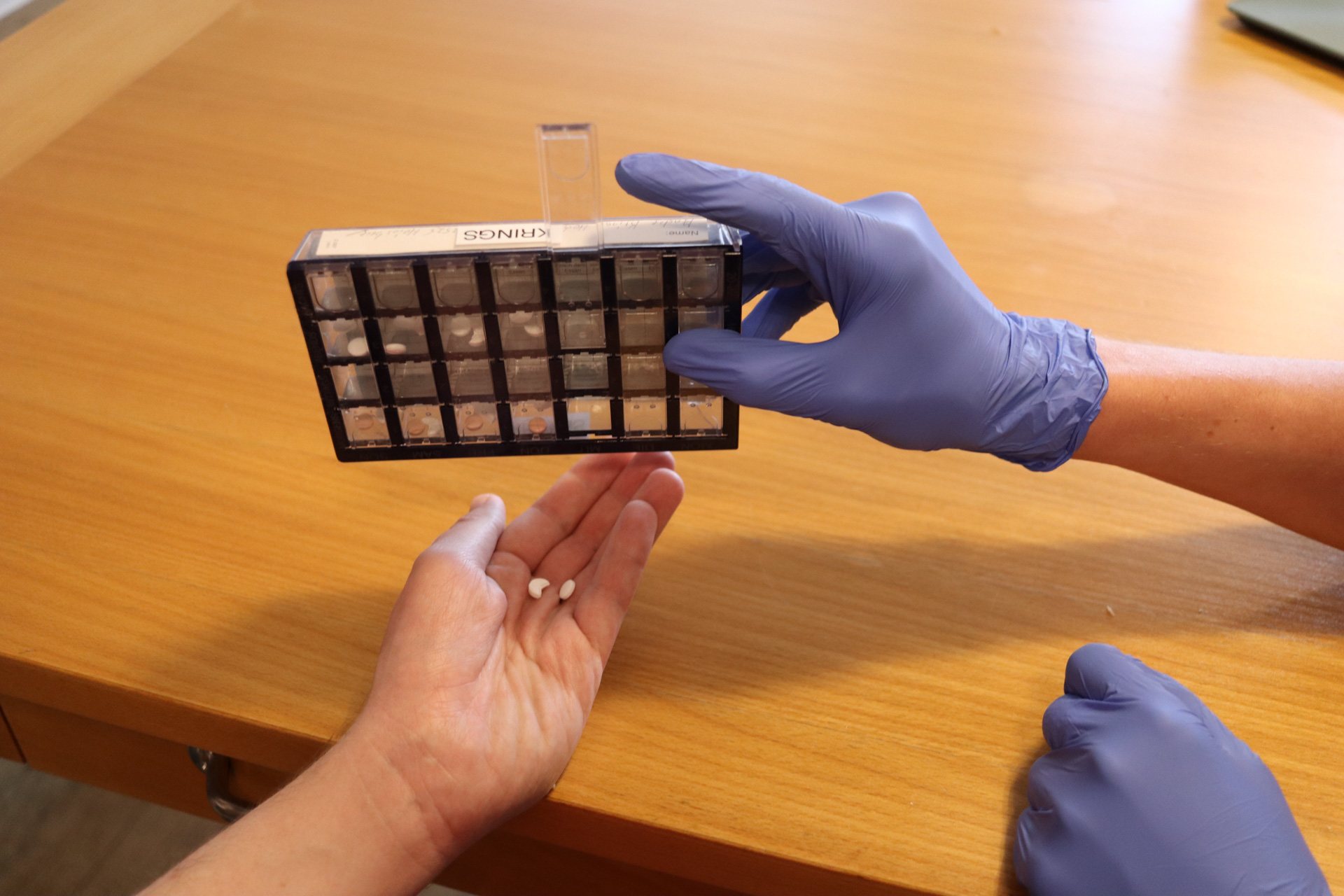 Eine Hand in einem Handschuh hält eine Tablette in der Hand.