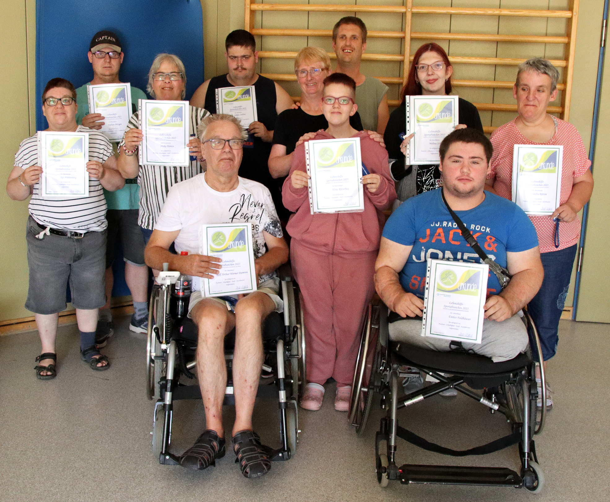 Ein Mann sitzt im Rollstuhl. Er hat ein rotes T-Shirt an. Er lächelt.