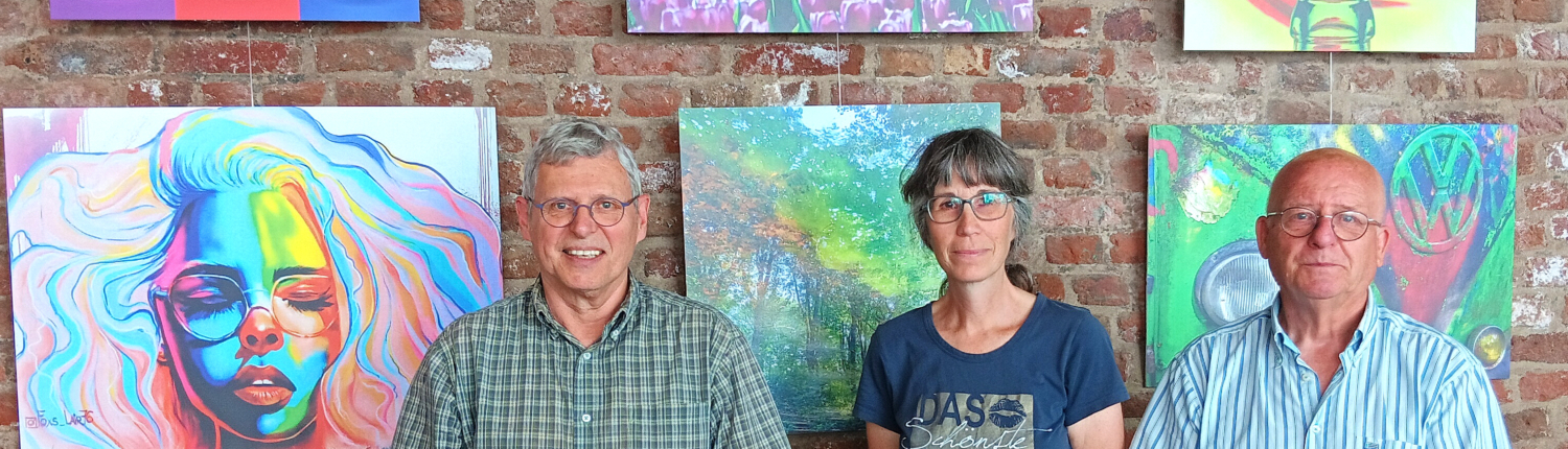 Zwei Personen stehen vor einem Bild. Das Bild zeigt ein Gesicht. Die Personen tragen Jeans und T-Shirts.