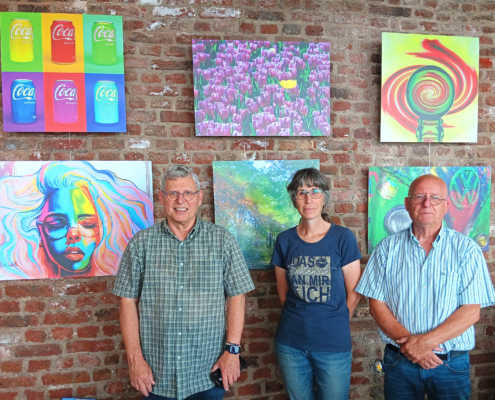 Zwei Personen stehen vor einem Bild. Das Bild zeigt ein Gesicht. Die Personen tragen Jeans und T-Shirts.