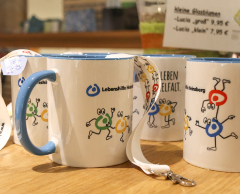 Zwei Tassen auf einem Tisch. Eine Tasse ist blau, die andere weiß.