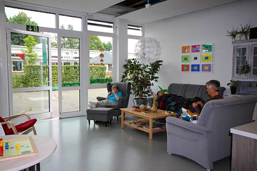 seniorengruppe Leute sitzen in einem Wohnzimmer. Es gibt viele Möbel und Pflanzen.