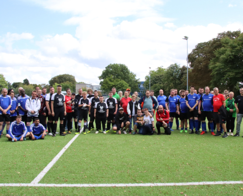 Eine Fußballmannschaft steht auf dem Spielfeld. Die Spieler stehen dicht aneinander.