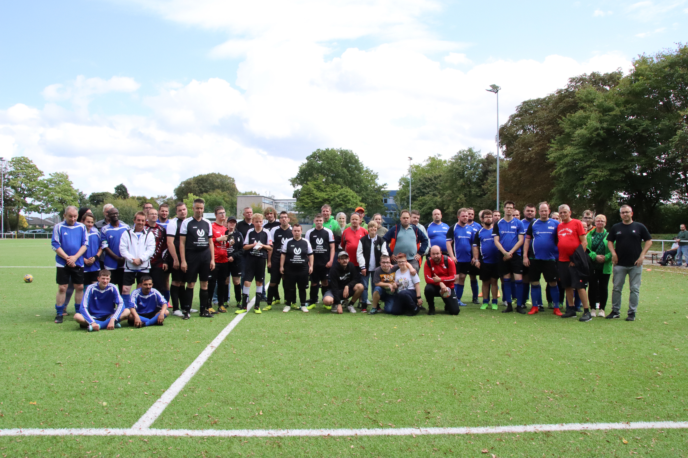 Eine Fußballmannschaft steht auf dem Spielfeld. Die Spieler stehen dicht aneinander.