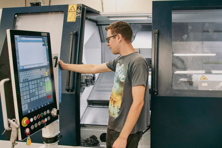 Ein Mann steht vor einer großen Maschine. Er berührt einen Bildschirm an der Maschine.