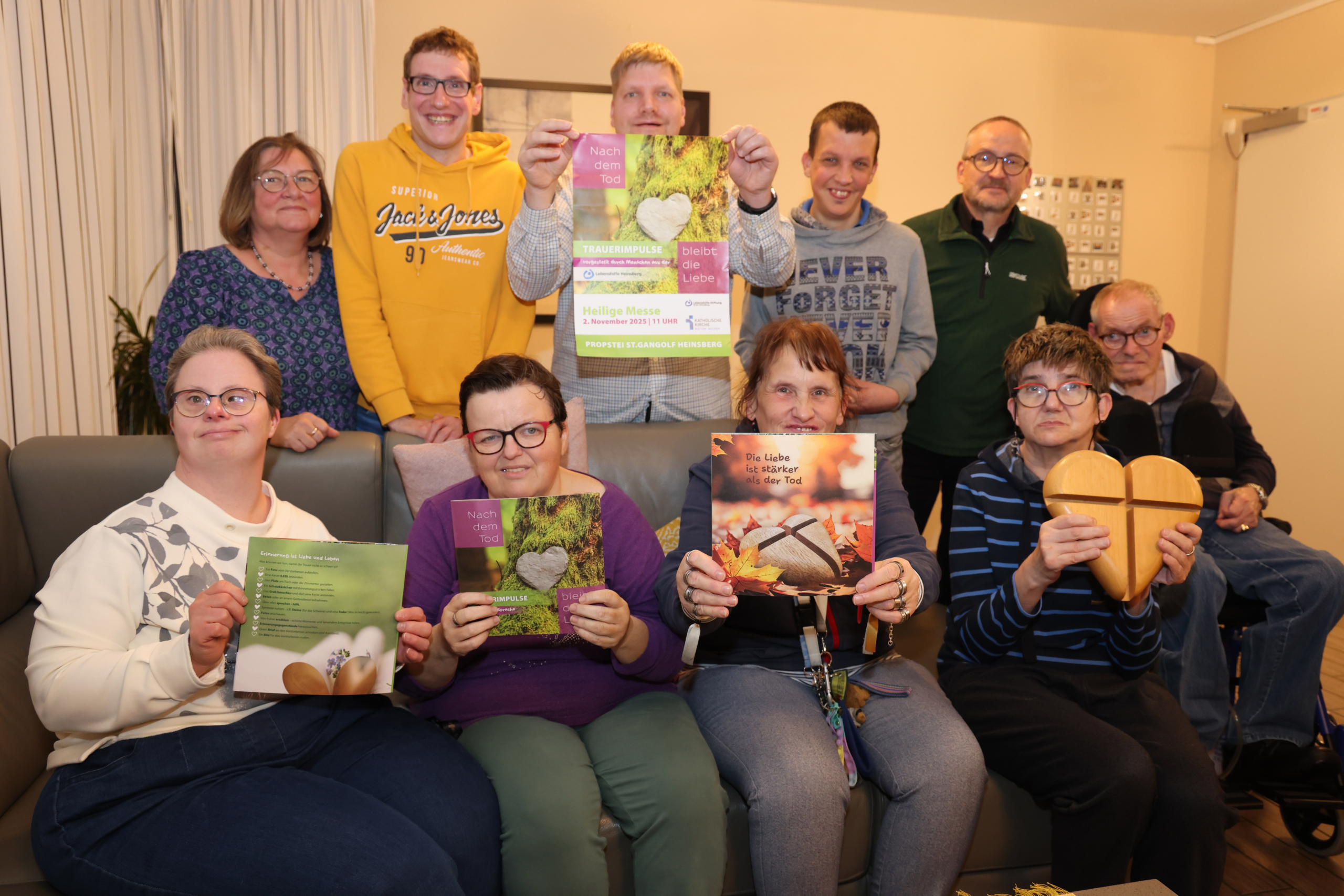 Menschen sitzen in einem Raum. Es gibt Möbel und Bilder an den Wänden.